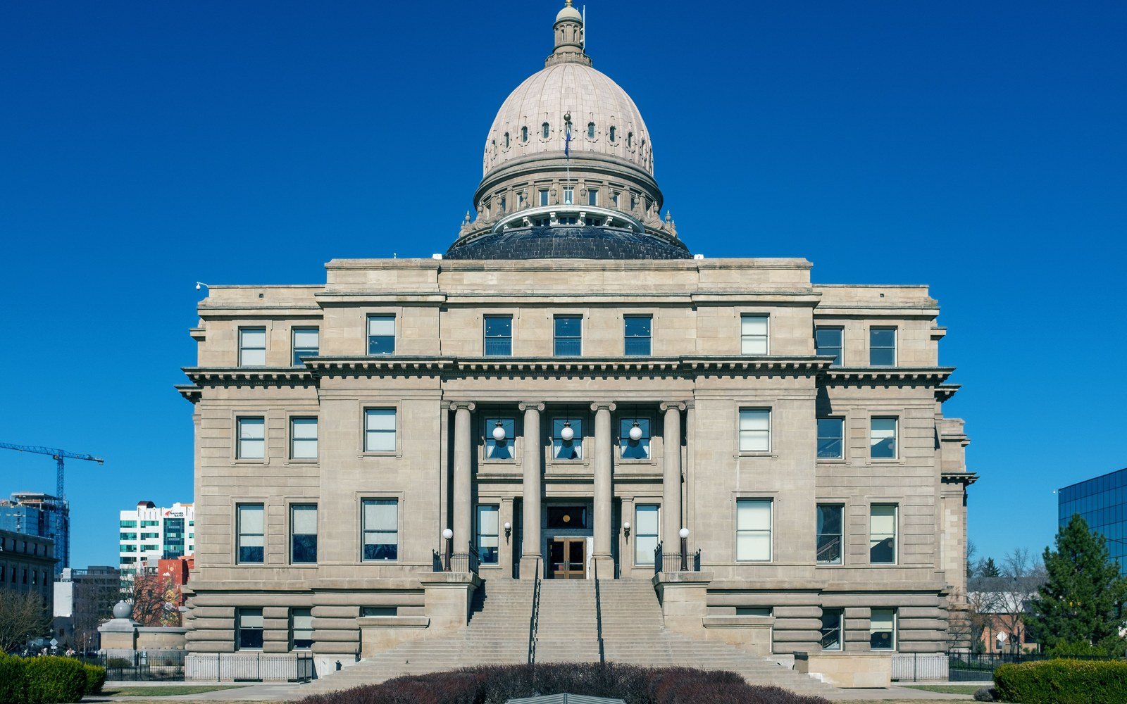 A stone civic building with a columned entrance below a ribbed dome, photographed straight on against a clear blue sky