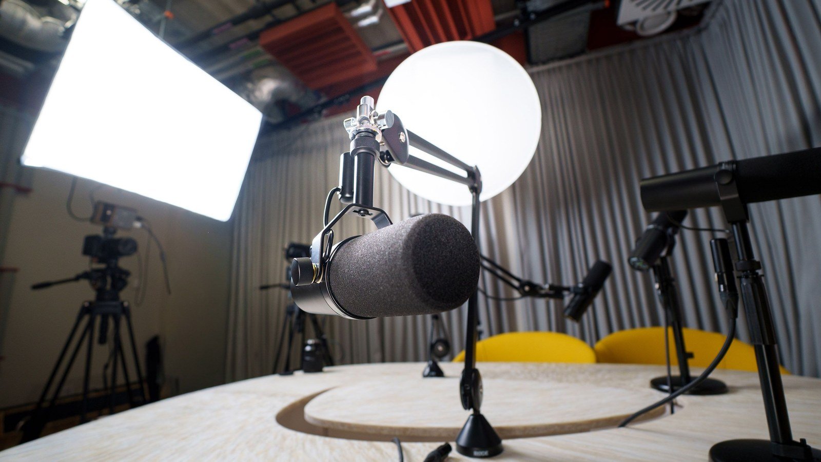 A microphone on a boom arm in a lit recording studio
