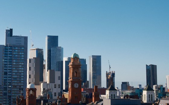 The Manchester skyline of towers and older red brick roofs under a clear blue sky