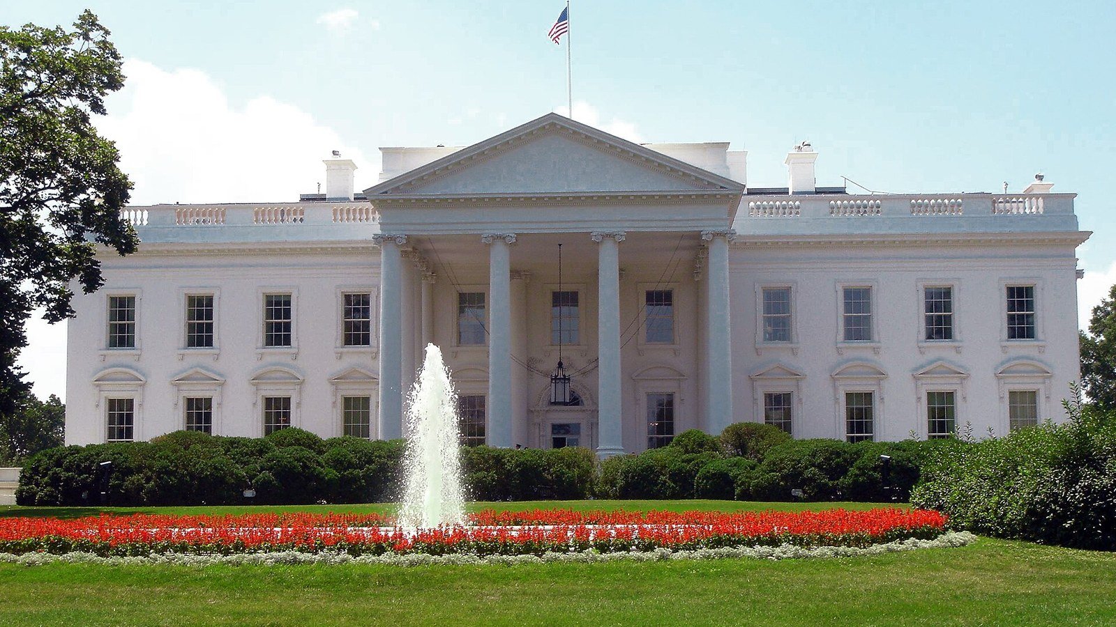 The north facade of the White House behind a fountain and flower beds