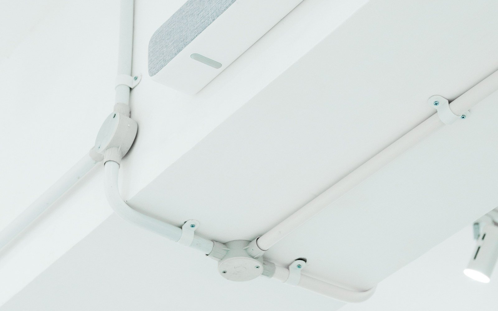 Surface mounted electrical conduit and containment running across a white ceiling