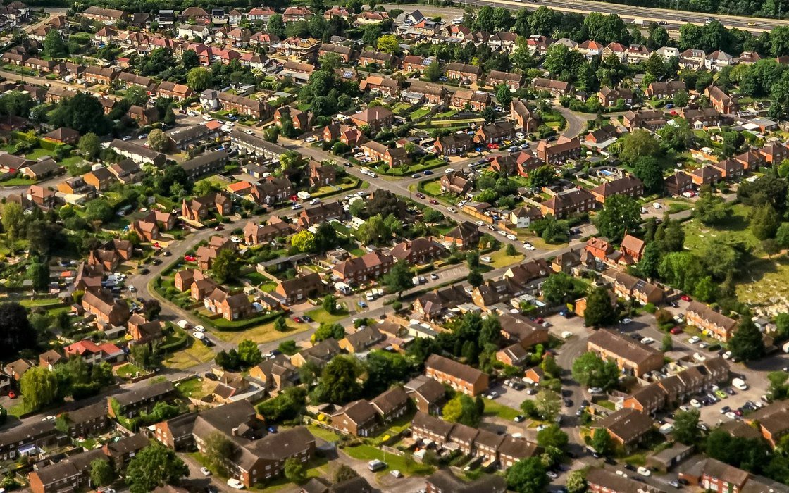 Aerial view of an English suburban housing area of pitched red tiled roofs, curving streets and mature trees