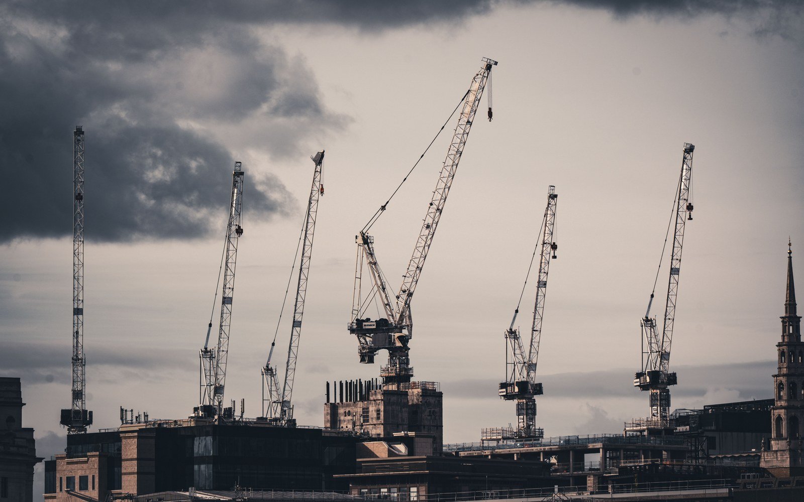 Tower cranes standing over rooftops on the London skyline at dusk