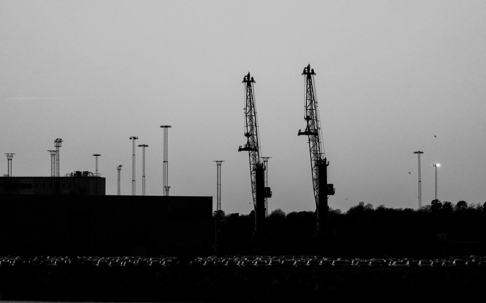 Silhouetted harbour cranes above a quayside at twilight