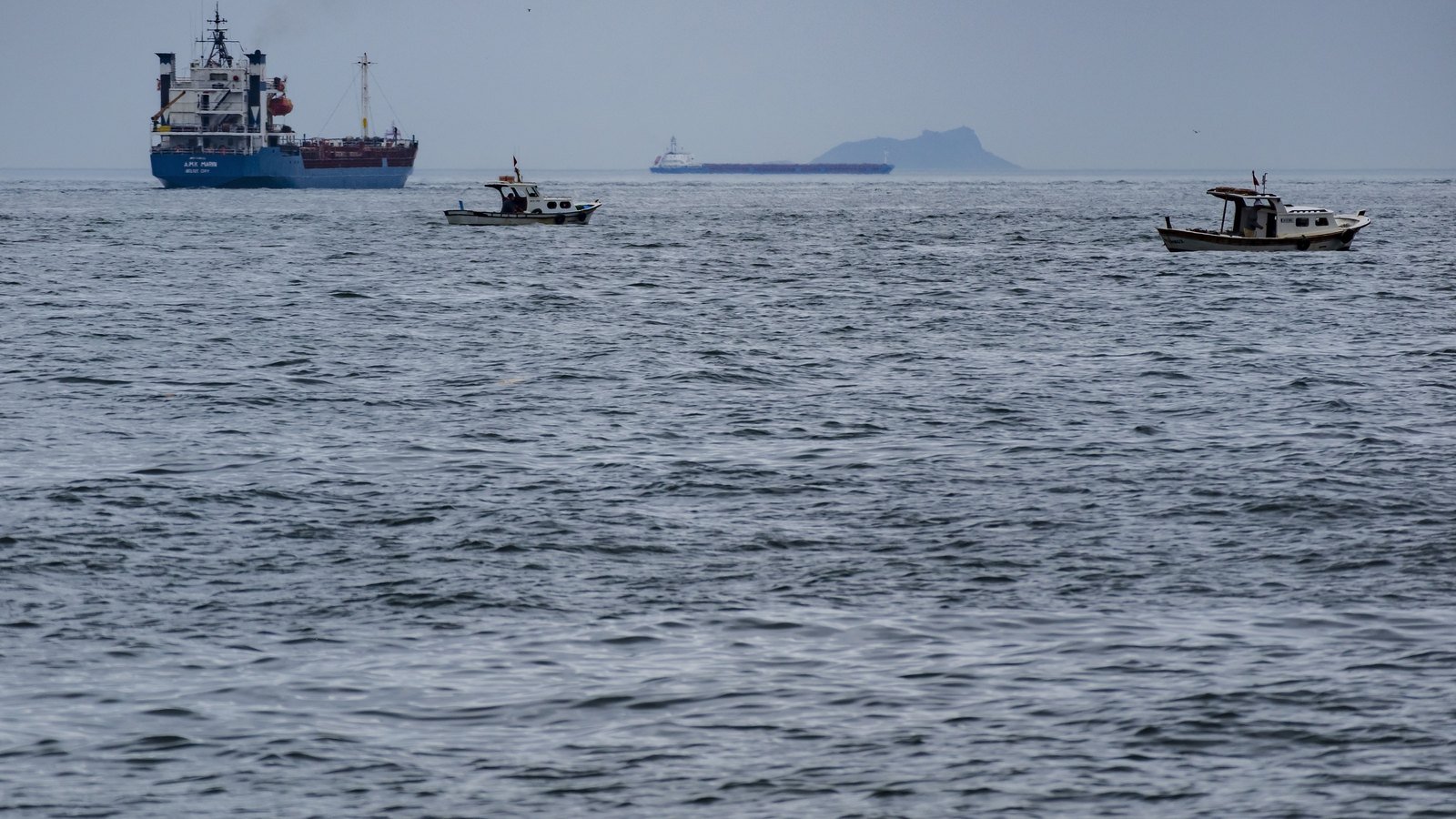 A cargo ship and a tanker on open water in the Sea of Marmara with two small fishing boats in the foreground