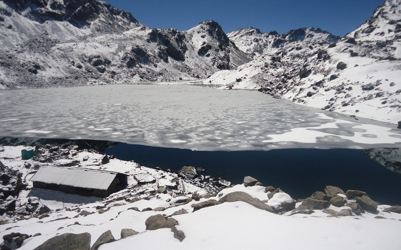 A frozen lake below snow covered peaks in the Rasuwa district of Nepal