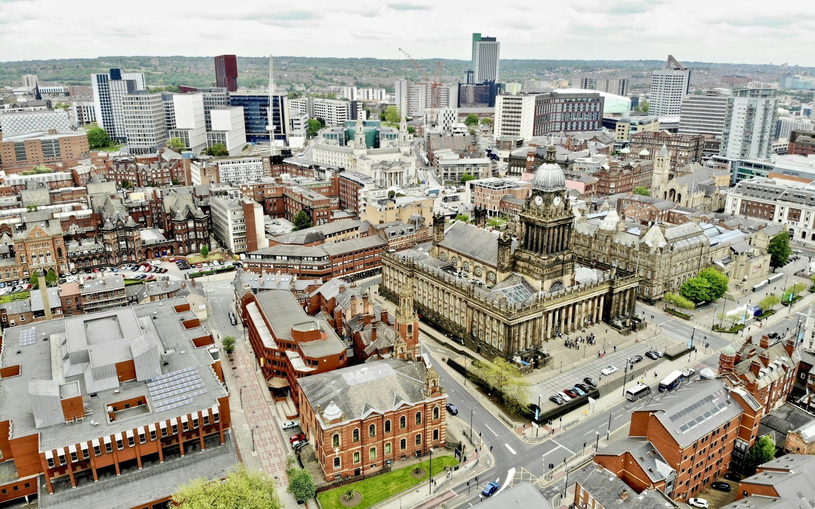 An oblique aerial photograph of a city centre, with a domed classical civic building among office blocks, terraces and tower cranes