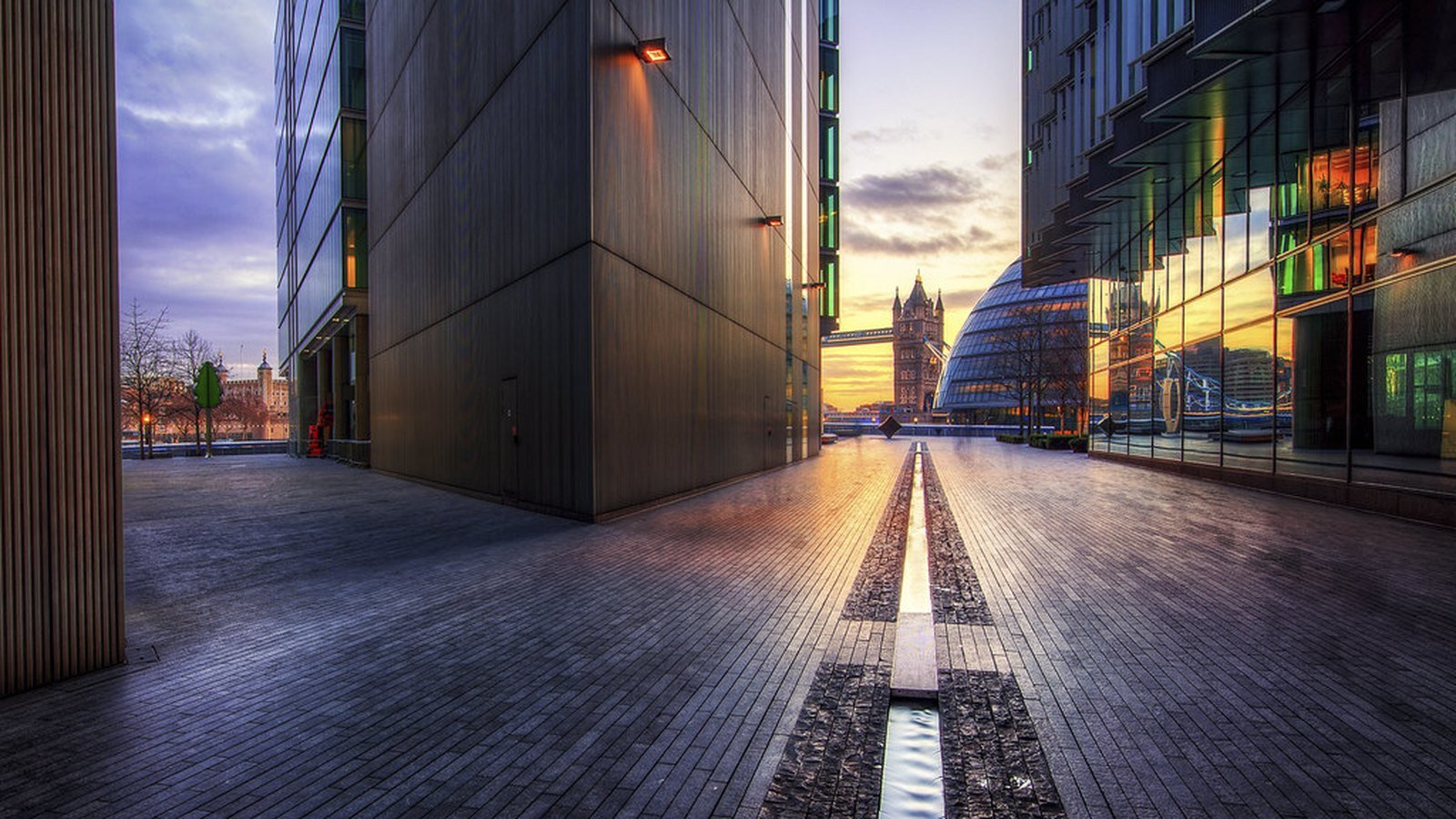 A paved walkway at dusk on the South Bank in London looking towards Tower Bridge and City Hall