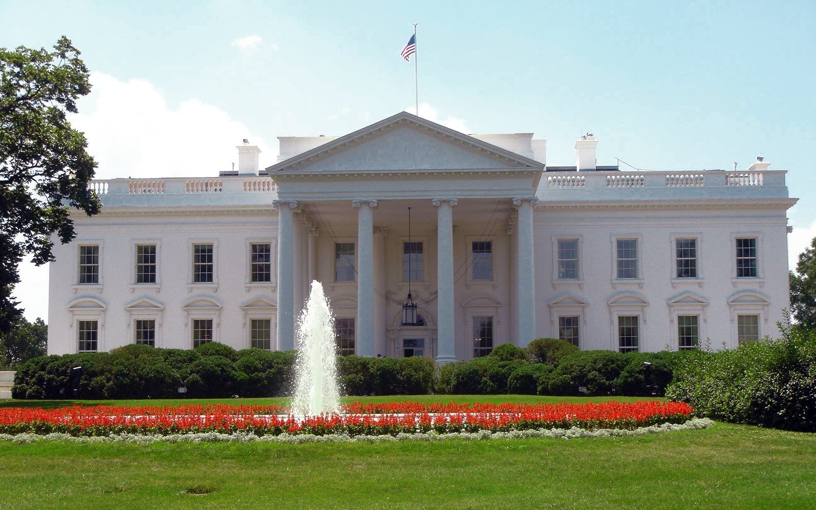 The north front of the White House behind its lawn and fountain on a clear day