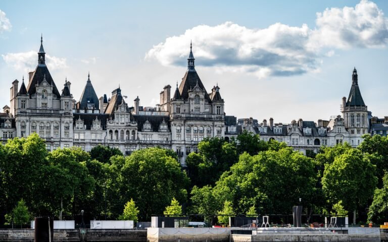 Historic buildings on Whitehall in London seen across trees on a sunny day