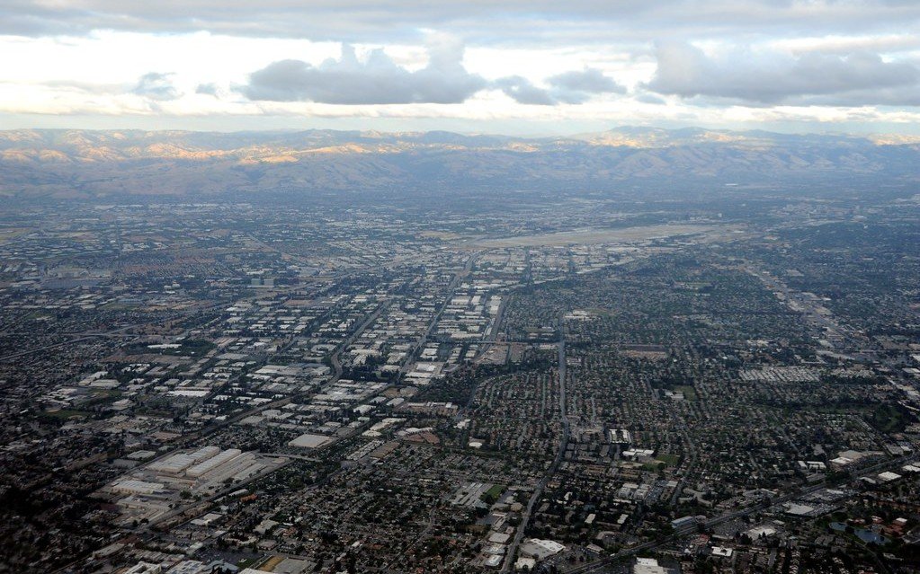 Low cloud over the hills above a wide spread of low buildings and suburban streets in Silicon Valley, seen from the air